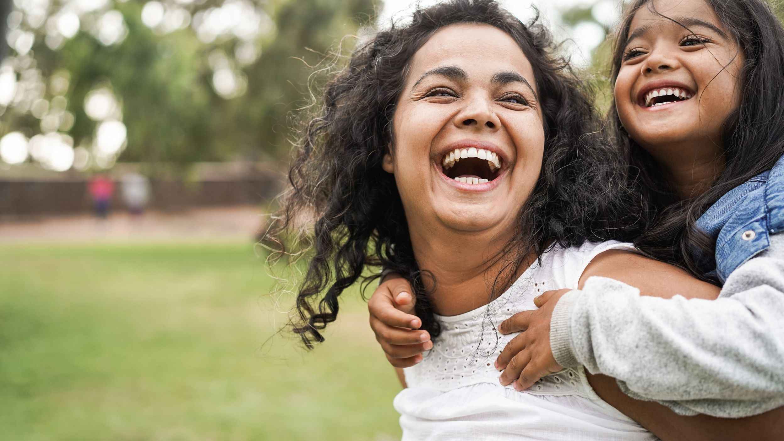 Laughing mom carrying her daughter on her back