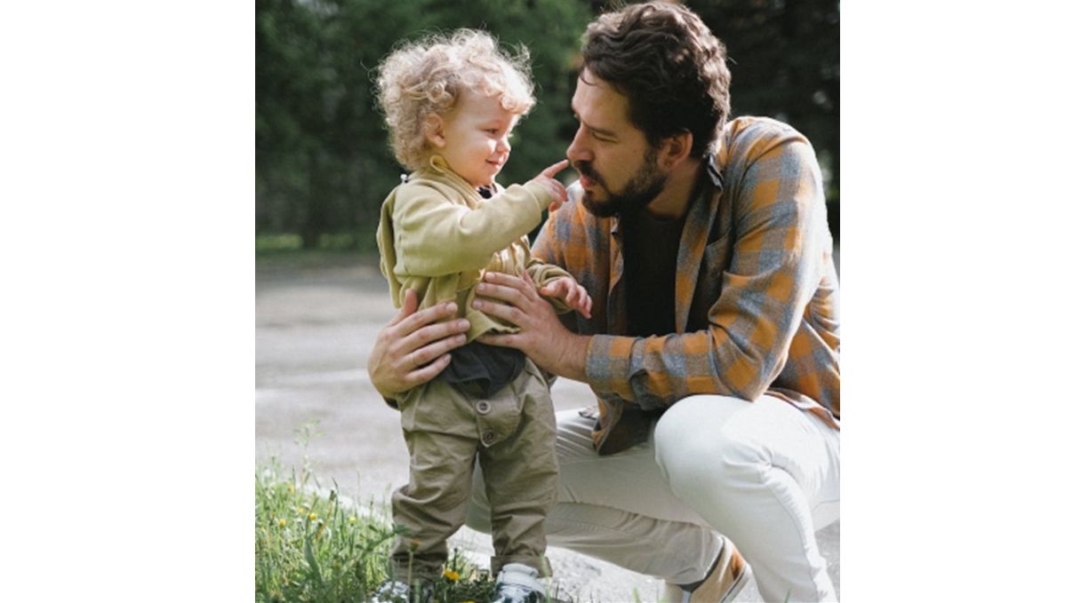 A dad holding and kneeling next to his son