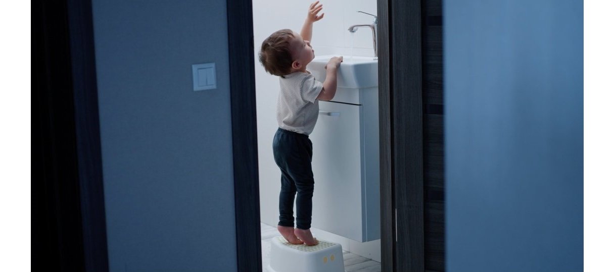 Toddler standing on a step stool as a basin