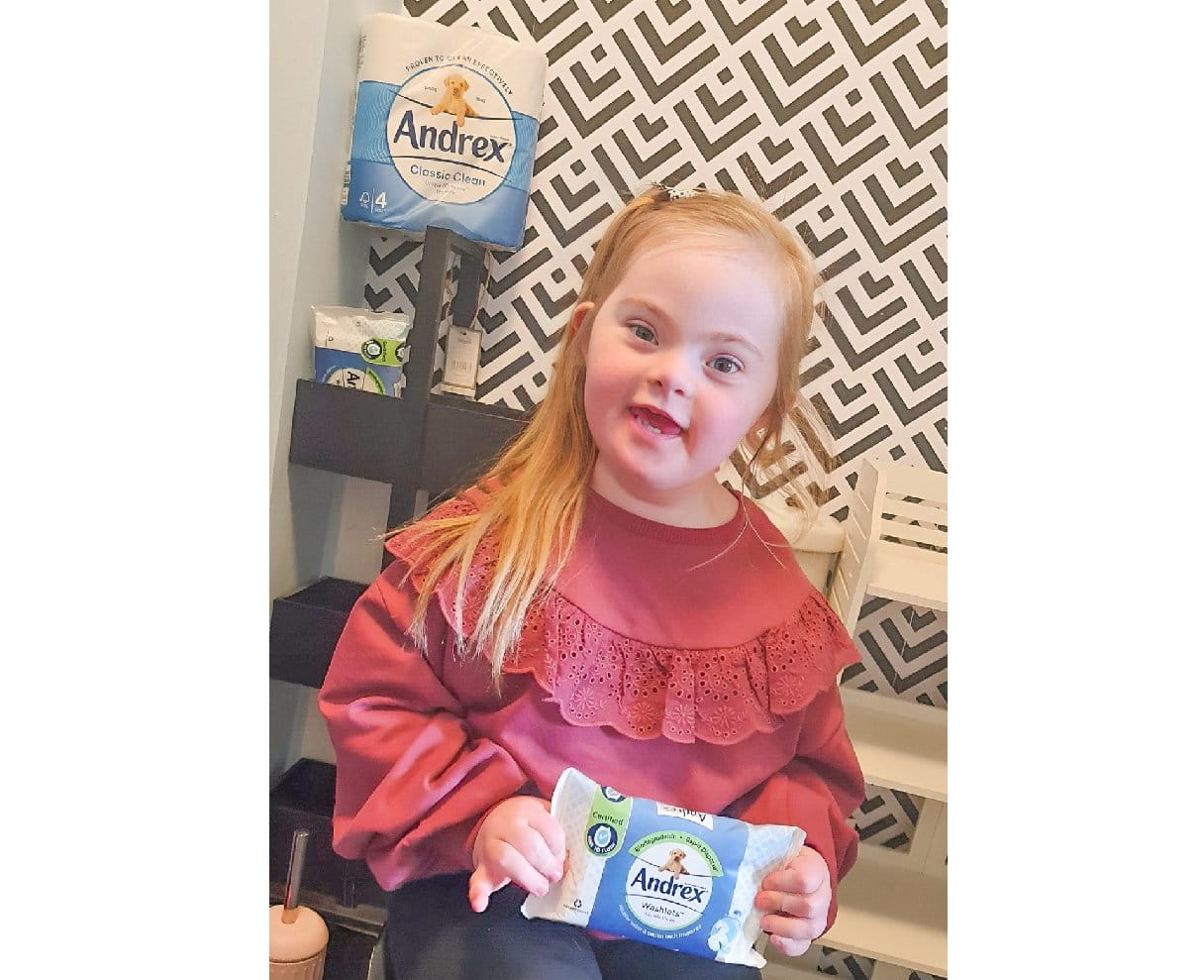 A smiling girl holding an Andrex Hygiene Wipes pack