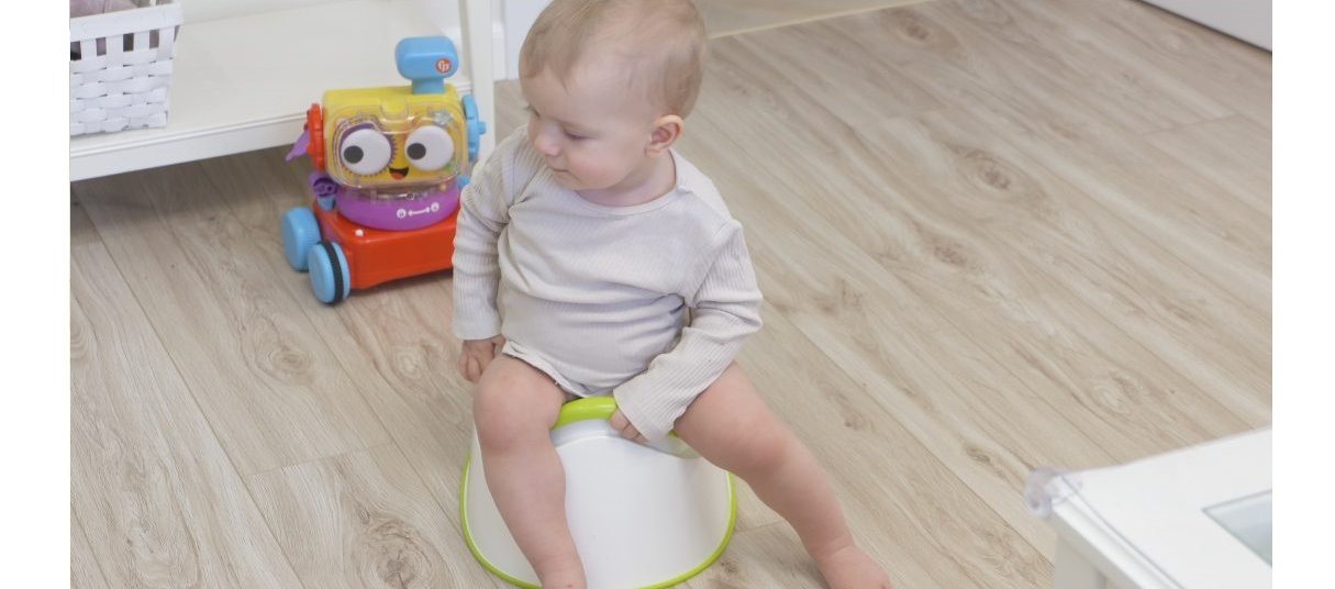 A toddler sitting on a potty next to their toy
