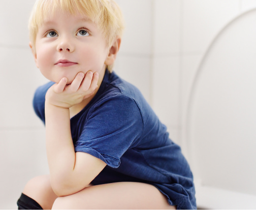 A boy busy daydreaming while sitting on the toilet