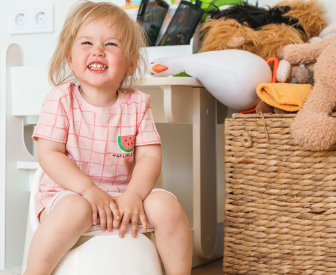 A girl sitting on her potty in a playroom